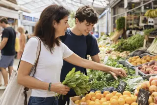 Two people selecting fresh vegetables and fruits together at an open market, engaged in a positive, natural conversation under soft daylight.